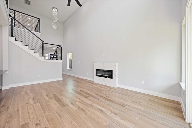 4923 Golden Forest Dr, Houston, TX 77091 - unfurnished living room with a towering ceiling, light wood-style floors, stairs, baseboards, and ceiling fan