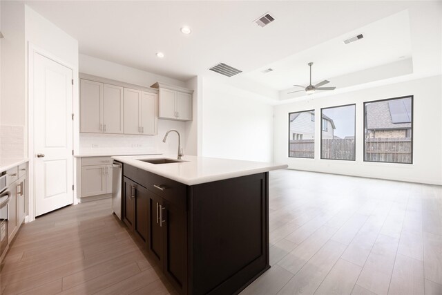 833 Laguna Green Ln, Katy, TX 77493 - kitchen featuring a raised ceiling, a sink, light wood finished floors, a ceiling fan, and light countertops