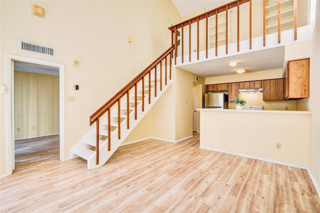 6103 Ludington Dr Unit 4-941, Houston, TX 77035 - unfurnished living room featuring light wood-type flooring, stairs, and a towering ceiling