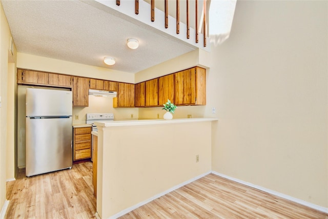 6103 Ludington Dr Unit 4-941, Houston, TX 77035 - kitchen with freestanding refrigerator, under cabinet range hood, light wood-style floors, and brown cabinetry