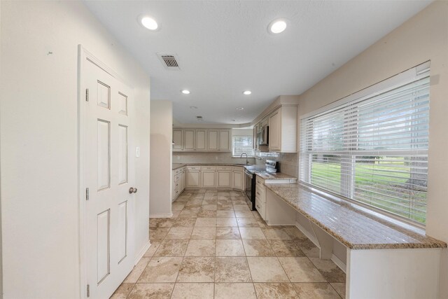 31302 Wisteria Rd, Magnolia, TX 77355 - kitchen with appliances with stainless steel finishes, cream cabinets, tasteful backsplash, recessed lighting, and light stone counters