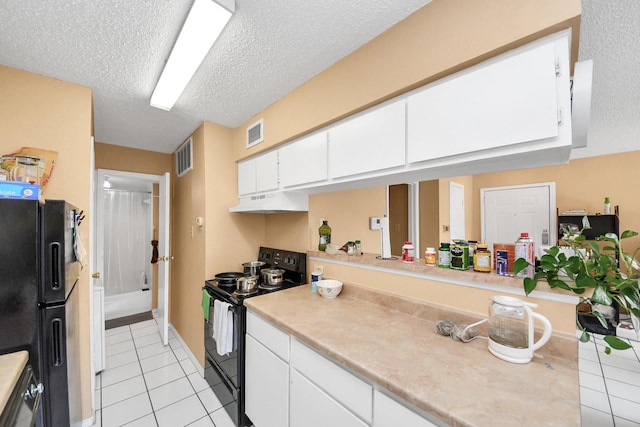 2750 Holly Hall St Unit 1104, Houston, TX 77054 - kitchen featuring black appliances, light tile patterned flooring, light countertops, white cabinetry, and a textured ceiling