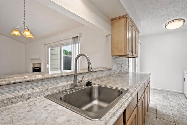 6493 Alisa Ln, Houston, TX 77084 - kitchen featuring a sink, a chandelier, a textured ceiling, decorative light fixtures, and a fireplace