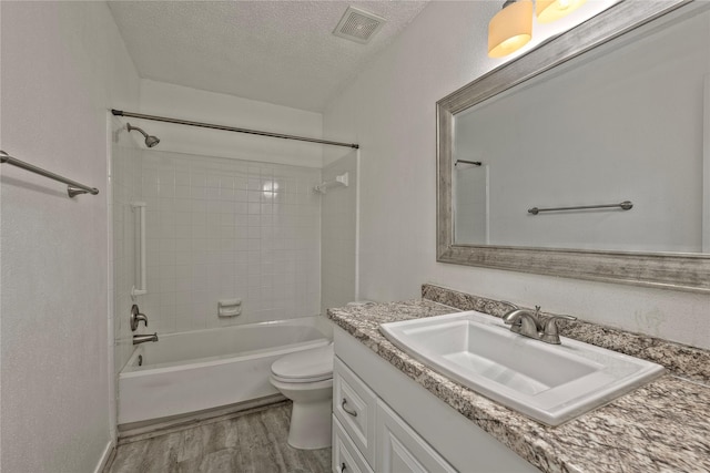 6493 Alisa Ln, Houston, TX 77084 - bathroom with vanity, wood finished floors, toilet, shower / bathtub combination, and a textured ceiling
