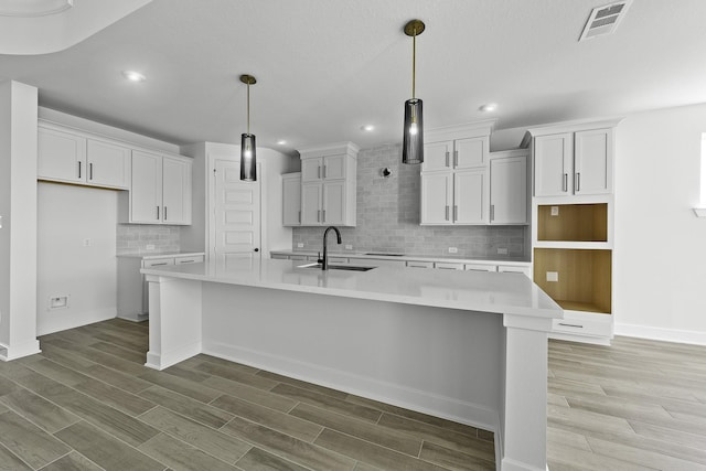 30419 Bermuda Hallow Bnd, Fulshear, TX 77423 - kitchen featuring a large island, recessed lighting, wood finished floors, backsplash, and white cabinets