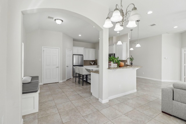311 W Independence Dr, League City, TX 77573 - kitchen featuring light tile patterned floors, a breakfast bar, white cabinets, arched walkways, and a chandelier