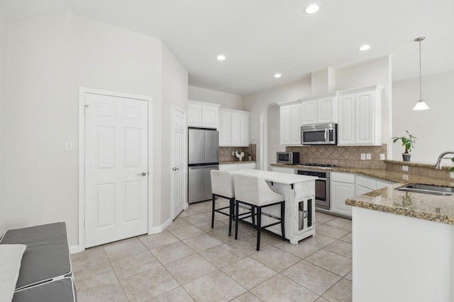 311 W Independence Dr, League City, TX 77573 - kitchen featuring appliances with stainless steel finishes, a sink, a breakfast bar area, tasteful backsplash, and white cabinets