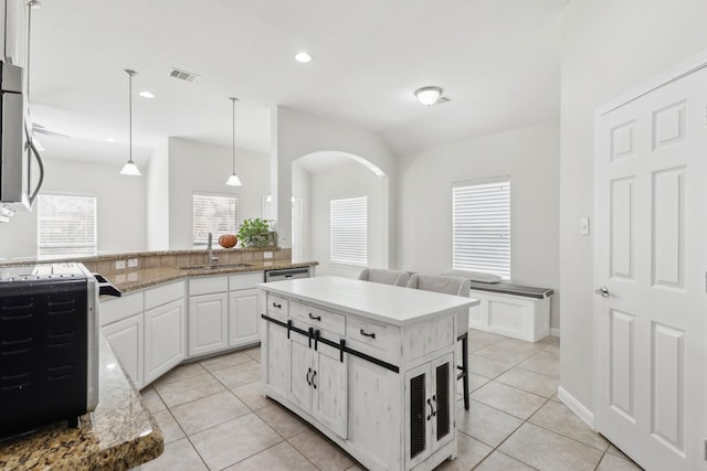 311 W Independence Dr, League City, TX 77573 - kitchen featuring a sink, white cabinets, light tile patterned floors, decorative light fixtures, and arched walkways