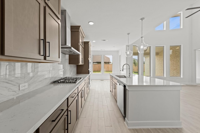 5041 Steady Breeze Dr, Katy, TX 77493 - kitchen featuring wall chimney range hood, appliances with stainless steel finishes, light wood-style floors, backsplash, and pendant lighting