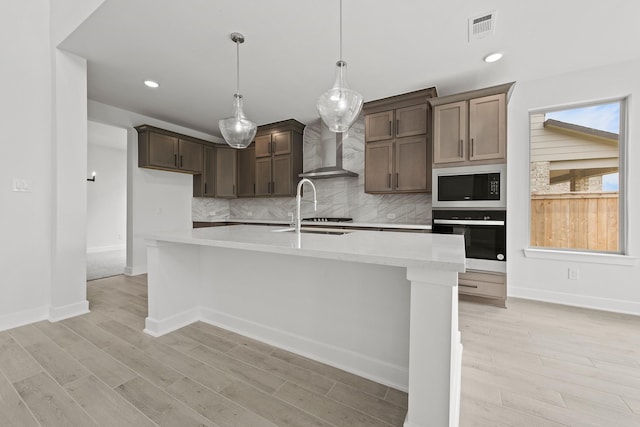 5041 Steady Breeze Dr, Katy, TX 77493 - kitchen with wall oven, wall chimney exhaust hood, built in microwave, tasteful backsplash, and light wood-style floors