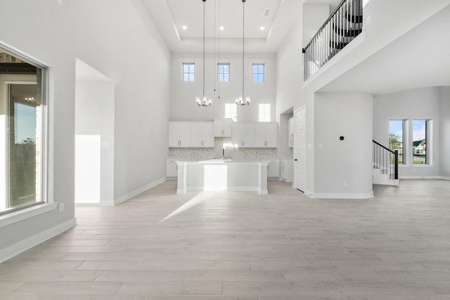 24727 Lobelia Garden Ln, Katy, TX 77493 - kitchen with open floor plan, a high ceiling, a chandelier, light wood finished floors, and a center island with sink