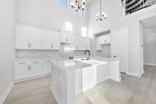 24727 Lobelia Garden Ln, Katy, TX 77493 - kitchen featuring a chandelier, a towering ceiling, a center island with sink, a sink, and tasteful backsplash