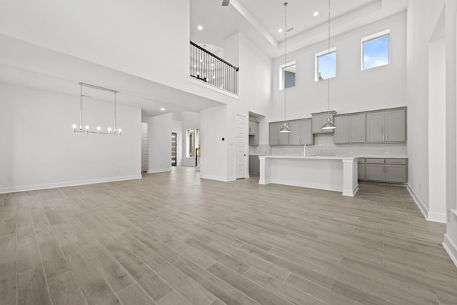 24718 Harrow Meadow Dr, Katy, TX 77493 - unfurnished living room with a towering ceiling, a sink, light wood-type flooring, baseboards, and recessed lighting