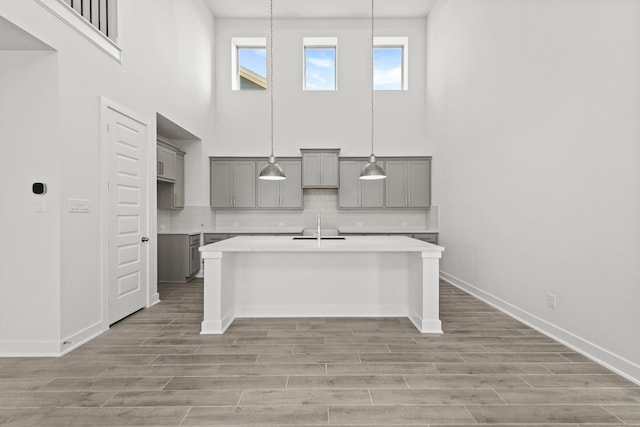 24718 Harrow Meadow Dr, Katy, TX 77493 - kitchen with gray cabinetry, light wood-type flooring, backsplash, a high ceiling, and a sink