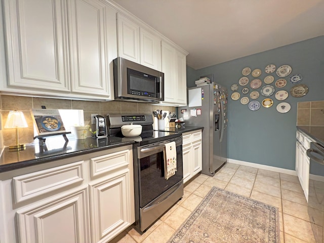 1919 Bailey St, Houston, TX 77006 - kitchen with stainless steel appliances, backsplash, dark countertops, light tile patterned floors, and white cabinets