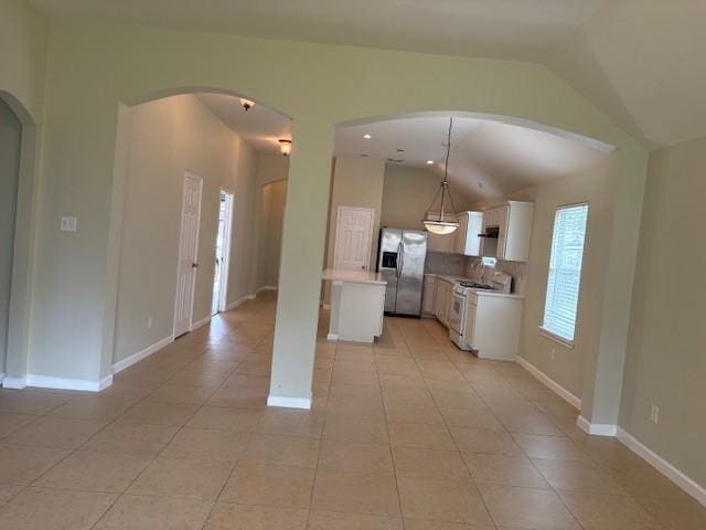 19119 Field Cottage Ln, Richmond, TX 77407 - kitchen featuring stainless steel fridge with ice dispenser, white range with gas stovetop, light countertops, light tile patterned floors, and vaulted ceiling