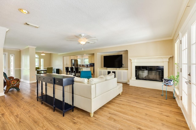 208 Fawn Trl, Lake Jackson, TX 77566 - living area featuring light wood-style floors, crown molding, ceiling fan, a glass covered fireplace, and a textured ceiling