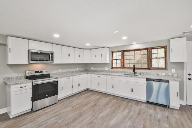 5419 Palmer St, Houston, TX 77004 - kitchen featuring appliances with stainless steel finishes, a sink, light wood-style flooring, white cabinetry, and light stone counters
