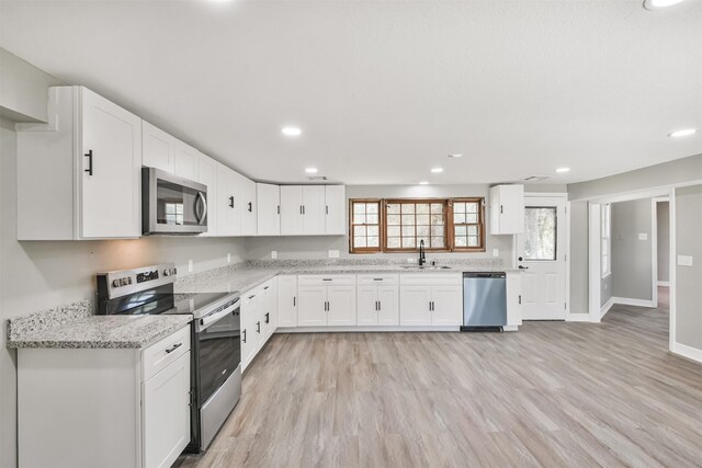 5419 Palmer St, Houston, TX 77004 - kitchen featuring stainless steel appliances, a sink, white cabinetry, light wood-type flooring, and recessed lighting