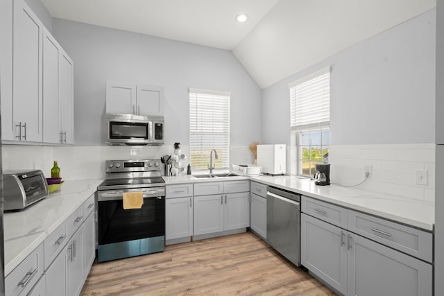 3582 County Road 476, Palacios, TX 77465 - kitchen with stainless steel appliances, a sink, vaulted ceiling, tasteful backsplash, and light stone countertops