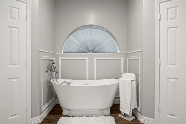 16022 Winchmore Hill Dr, Spring, TX 77379 - bathroom with a decorative wall, wood finished floors, a freestanding tub, and a wainscoted wall