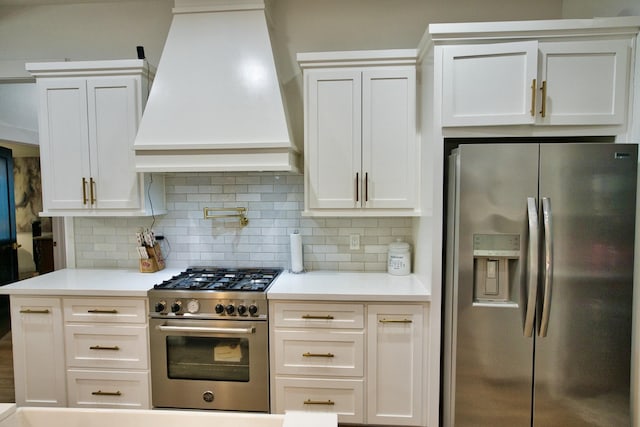 455 Green Meadows Dr, West Columbia, TX 77486 - kitchen featuring appliances with stainless steel finishes, premium range hood, tasteful backsplash, light countertops, and white cabinetry