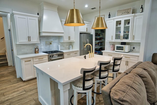 455 Green Meadows Dr, West Columbia, TX 77486 - kitchen with custom range hood, stainless steel appliances, tasteful backsplash, a kitchen bar, and glass insert cabinets