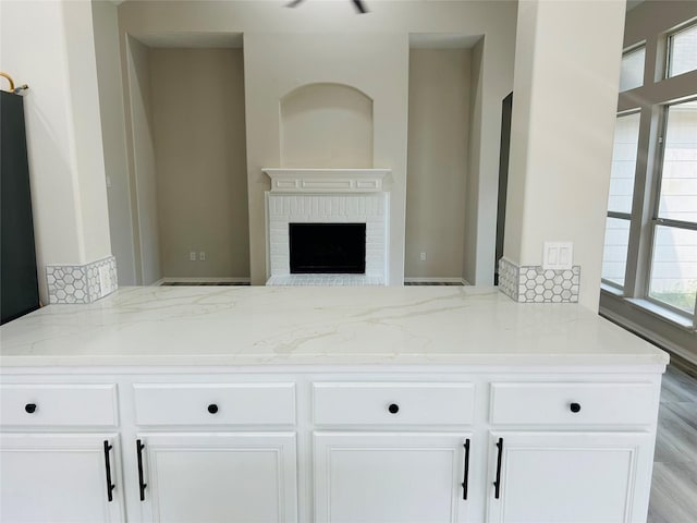21227 River Knoll Ln, Katy, TX 77449 - kitchen featuring light stone counters, white cabinets, a brick fireplace, and open floor plan