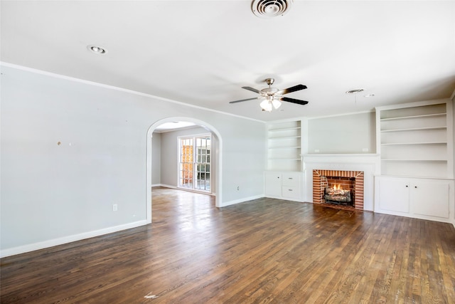 606 N Main St, Dayton, TX 77535 - unfurnished living room with a ceiling fan, baseboards, a brick fireplace, arched walkways, and dark wood-style floors