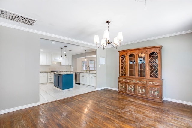 606 N Main St, Dayton, TX 77535 - kitchen featuring a sink, a chandelier, stainless steel appliances, light wood-style floors, and white cabinetry