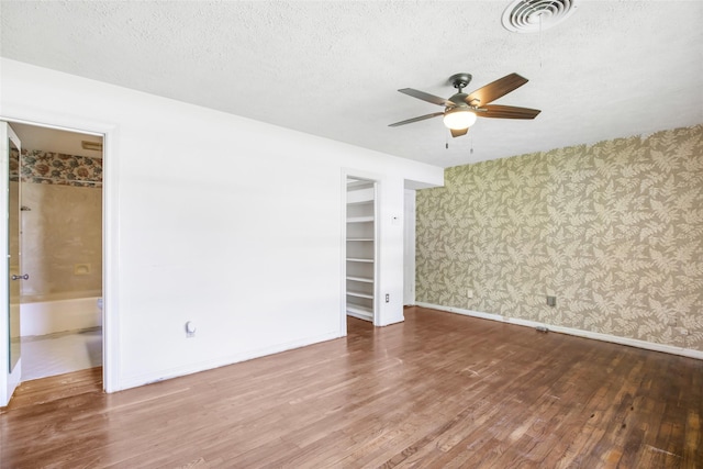 606 N Main St, Dayton, TX 77535 - spare room with wallpapered walls, a ceiling fan, wood finished floors, baseboards, and a textured ceiling