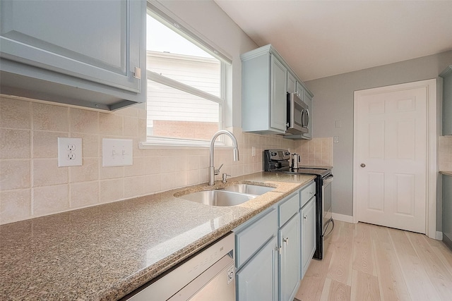 15251 Weeping Cedar Ln, Houston, TX 77084 - kitchen featuring a sink, stainless steel appliances, light wood-type flooring, tasteful backsplash, and light stone countertops