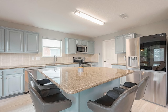 15251 Weeping Cedar Ln, Houston, TX 77084 - kitchen with stainless steel appliances, a sink, a center island, a kitchen bar, and decorative backsplash