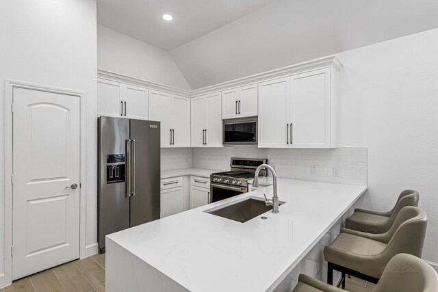 24203 Leonforte Dr, Richmond, TX 77406 - kitchen featuring stainless steel appliances, a sink, white cabinets, vaulted ceiling, and recessed lighting