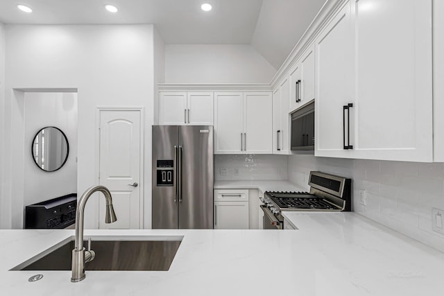 24203 Leonforte Dr, Richmond, TX 77406 - kitchen with appliances with stainless steel finishes, a sink, white cabinetry, tasteful backsplash, and vaulted ceiling