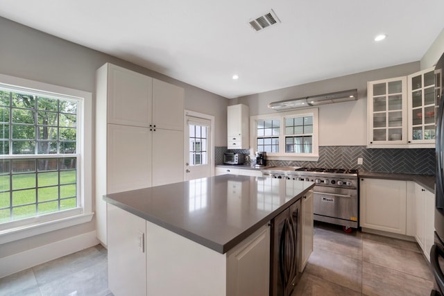 3222 Oakmont St, Houston, TX 77021 - kitchen with dark countertops, backsplash, a center island, glass insert cabinets, and recessed lighting