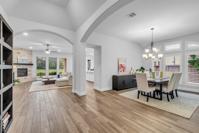28249 Woodland Bend Way, Spring, TX 77386 - dining room featuring ceiling fan, wood finished floors, a tiled fireplace, arched walkways, and high vaulted ceiling