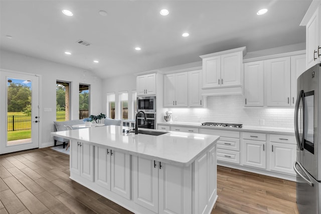 28249 Woodland Bend Way, Spring, TX 77386 - kitchen featuring stainless steel appliances, a center island with sink, a sink, backsplash, and light countertops