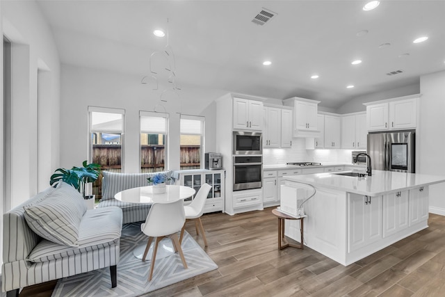 28249 Woodland Bend Way, Spring, TX 77386 - kitchen with appliances with stainless steel finishes, a sink, light countertops, wood finished floors, and white cabinets