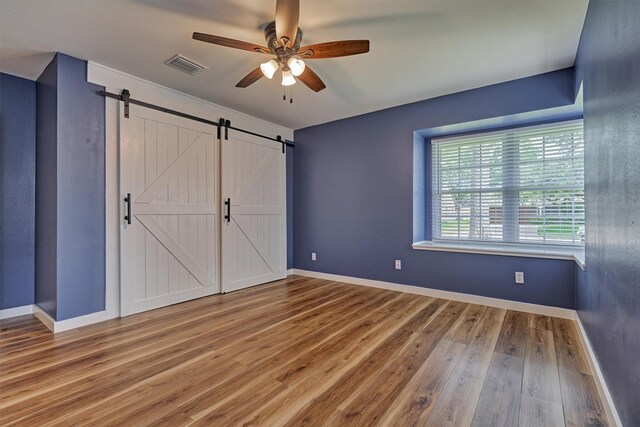 10411 Londonderry Dr, Houston, TX 77043 - unfurnished bedroom featuring a barn door, wood finished floors, baseboards, and ceiling fan