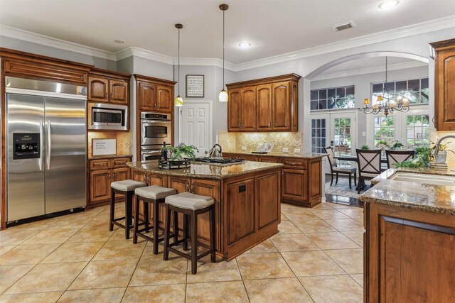 7014 Lake Haven Ct, Sugar Land, TX 77479 - kitchen featuring built in appliances, a sink, a chandelier, a center island with sink, and stone counters