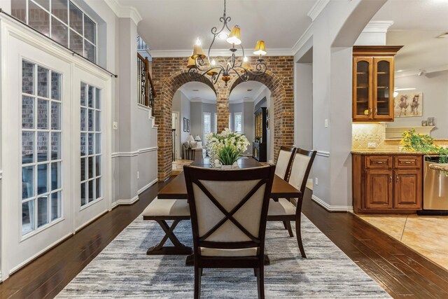 7014 Lake Haven Ct, Sugar Land, TX 77479 - dining space with arched walkways, a chandelier, hardwood / wood-style flooring, ornamental molding, and ornate columns