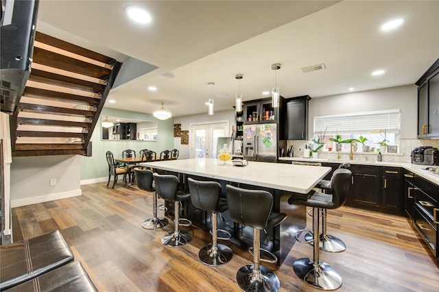 2246 Triway Ln, Houston, TX 77043 - kitchen featuring stainless steel refrigerator with ice dispenser, a breakfast bar, a center island, backsplash, and plenty of natural light