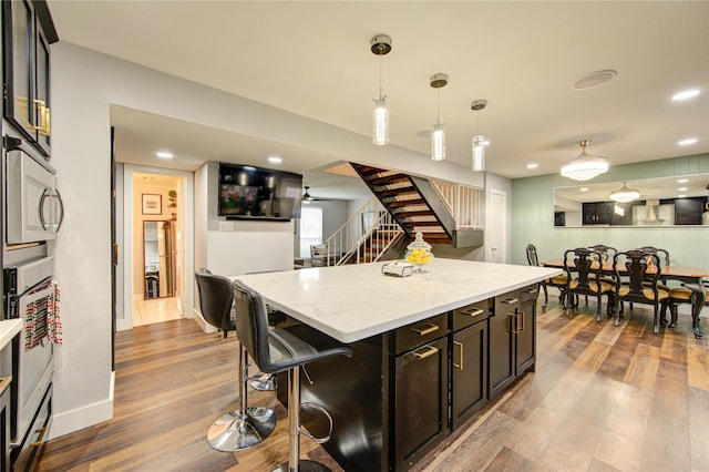 2246 Triway Ln, Houston, TX 77043 - kitchen featuring wood finished floors, pendant lighting, light stone counters, a kitchen breakfast bar, and a kitchen island