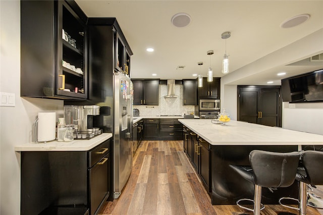 2246 Triway Ln, Houston, TX 77043 - kitchen with appliances with stainless steel finishes, wall chimney range hood, dark cabinets, a center island, and wood finished floors