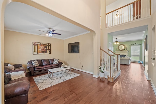 8910 Cote Ct, Houston, TX 77064 - living room with a ceiling fan, arched walkways, wood finished floors, crown molding, and a fireplace