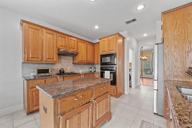 8910 Cote Ct, Houston, TX 77064 - kitchen featuring black appliances, under cabinet range hood, tasteful backsplash, light tile patterned floors, and a kitchen island