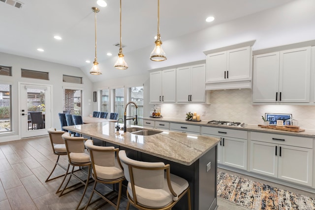17185 Foxtrot Way, Conroe, TX 77302 - kitchen featuring a sink, tasteful backsplash, an island with sink, a kitchen breakfast bar, and light stone countertops