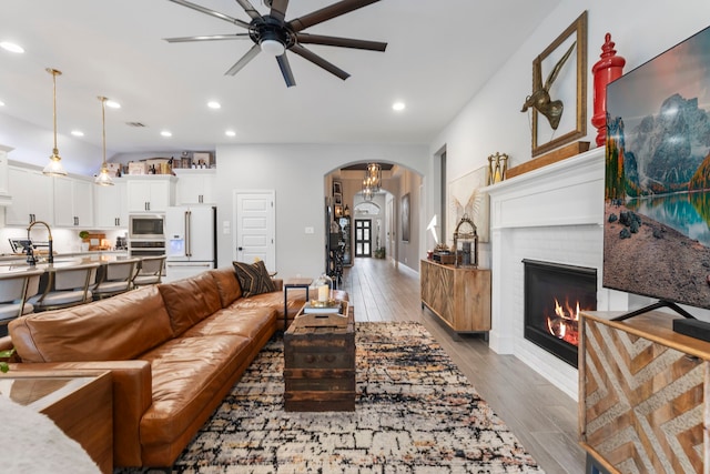 17185 Foxtrot Way, Conroe, TX 77302 - living area with arched walkways, a ceiling fan, wood finished floors, a brick fireplace, and recessed lighting
