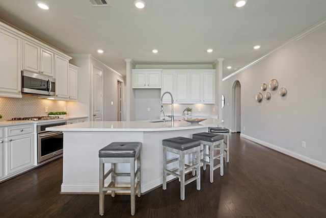 18735 Evanhale Bend Dr, Cypress, TX 77429 - kitchen with stainless steel appliances, a sink, a kitchen island with sink, arched walkways, and crown molding